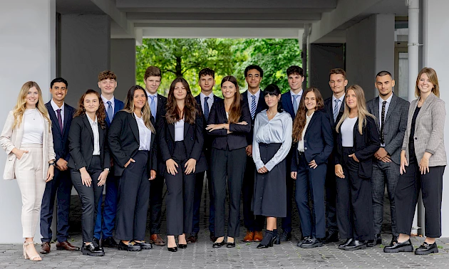 Foto: Katharina Hein --- Die 15 neuen Auszubildenden der Volksbank Oberberg zusammen mit Ausbildungsleiterin Sarina Scherbaum (links) und Lisa Marie Dresbach (Volksbank Akademie, rechts).