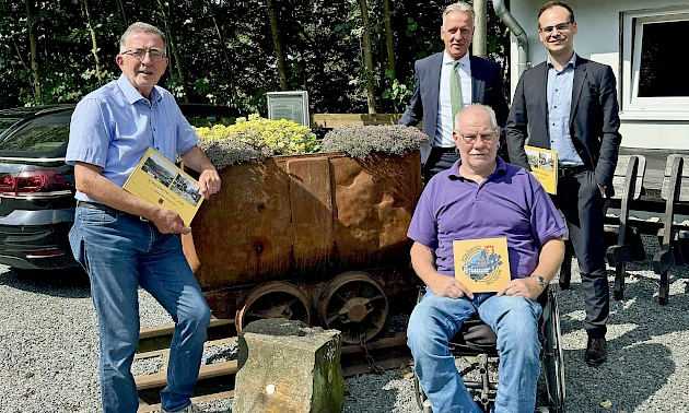 Foto: Volksbank Oberberg --- Vorstandsvorsitzender Ingo Stockhausen (hinten links) warf einen ersten Blick in das von Dr. Frank Gelhausen (vorne) und Christoph Gissinger (links) zusammengestellten Bildband über Ründeroth.