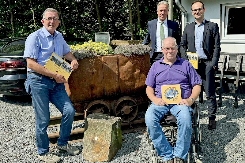 Foto: Volksbank Oberberg --- Vorstandsvorsitzender Ingo Stockhausen (hinten links) warf einen ersten Blick in das von Dr. Frank Gelhausen (vorne) und Christoph Gissinger (links) zusammengestellten Bildband über Ründeroth.