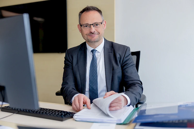Thomas Rickmann sitzt an einem Schreibtisch vor einem Computer. Er ist Experte für Generationenmanagement und Ruhestandsplanung bei der Volksbank Oberberg.“