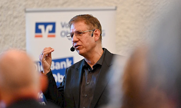 Nahaufnahme von Dr. Jens-Uwe Meyer, der mittels Headset zum Publikum spircht.