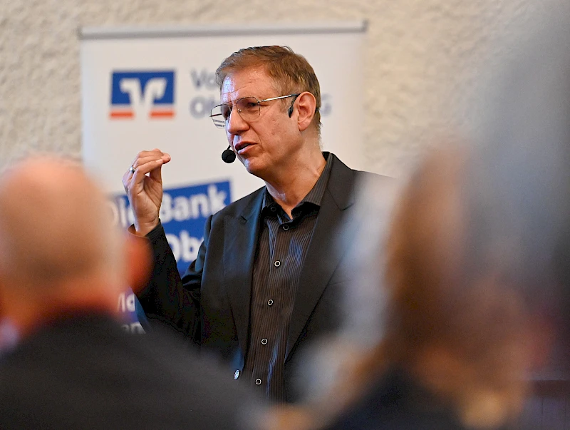 Nahaufnahme von Dr. Jens-Uwe Meyer, der mittels Headset zum Publikum spircht.