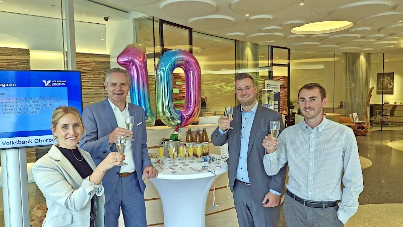 Vier Personen stoßen anlässlich des 10-jährigen Jubiläums der Geschäftsstelle Forum Gummersbach der Volksbank Oberberg an. Von links: Miriam Elsner, Niederlassungsleiter Henning Zöller, Geschäftsstellenleiter Justin Wagner und Mika Steeg. Sie lächeln und