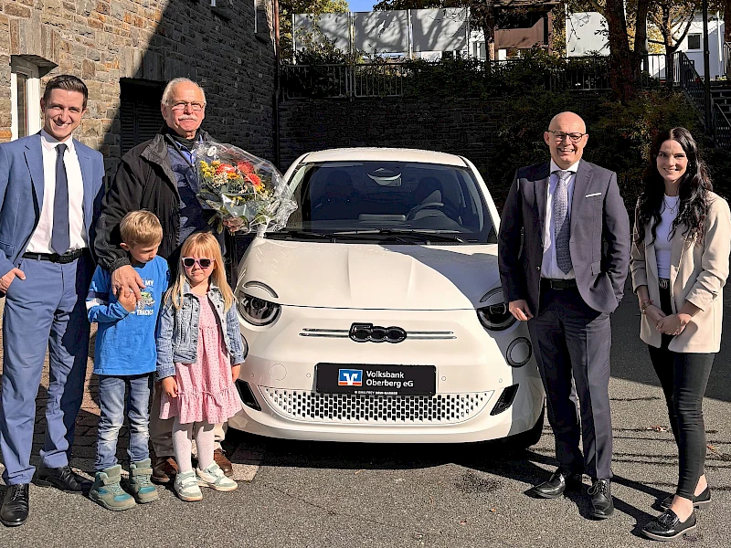 Gewinner Karl-Heinz Altmann steht mit seinen Enkeln und drei Volksbank-Mitarbeitern vor seinem neuen Auto.