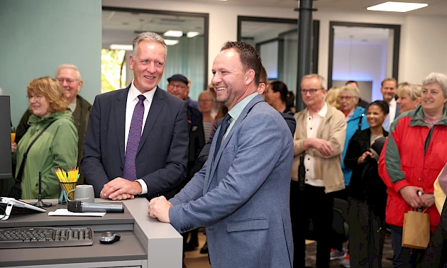 Ingo Stockhausen und Stefan Rappenhöner stehen bei der Eröffnung der modernisierten Volksbank-Geschäftsstelle in Drabenderhöhe, im Hintergrund mehrere Besucherinnen und Besucher der Veranstaltung.