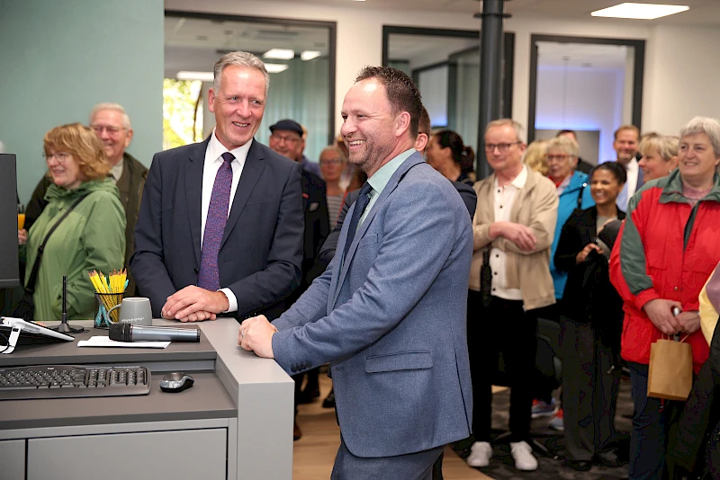Ingo Stockhausen und Stefan Rappenhöner stehen bei der Eröffnung der modernisierten Volksbank-Geschäftsstelle in Drabenderhöhe, im Hintergrund mehrere Besucherinnen und Besucher der Veranstaltung.