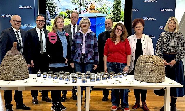 Bei der Spendenübergabe in Wiehl überreichen Vertreter der Volksbank Oberberg Honig aus eigener Herstellung und 15.000 € an Vertreterinnen und Vertreter der oberbergischen Tafeln.
