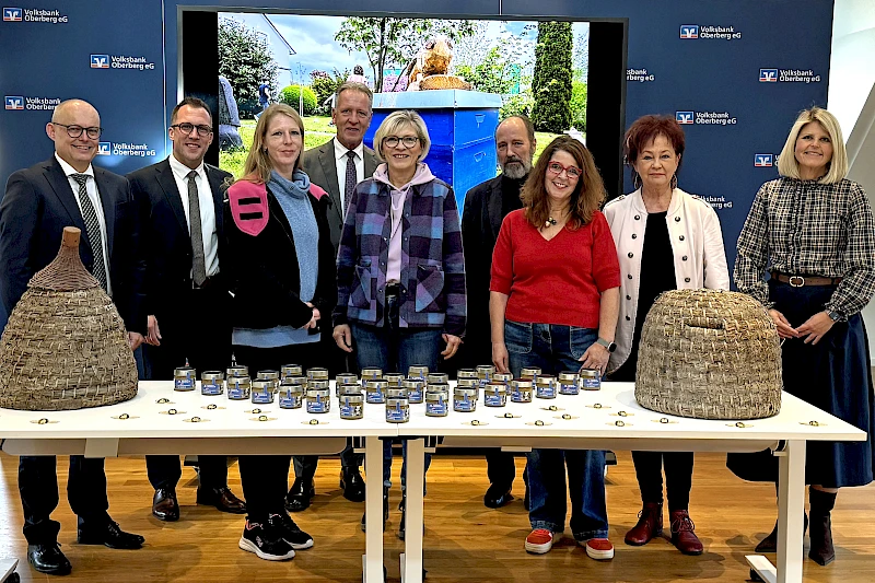 Bei der Spendenübergabe in Wiehl überreichen Vertreter der Volksbank Oberberg Honig aus eigener Herstellung und 15.000 € an Vertreterinnen und Vertreter der oberbergischen Tafeln.