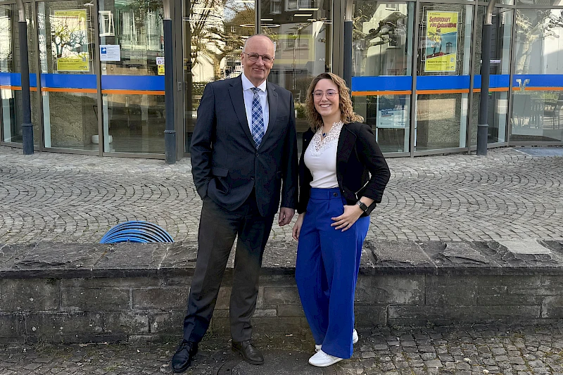 Niederlassungsleiter Stefan Weise und Geschäftsstellenleiterin Pia Wippenbeck stehen nebeneinander vor der Geschäftsstelle Engelskirchen und lächeln.