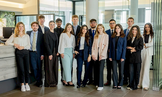 14 neue Auszubildende der Volksbank Oberberg stehen gemeinsam mit Ausbildungsleiterin Sarina Scherbaum in der Hauptstelle in Wiehl. Die Gruppe lächelt in die Kamera und markiert den gemeinsamen Start in die Ausbildung zum 1. August 2026.