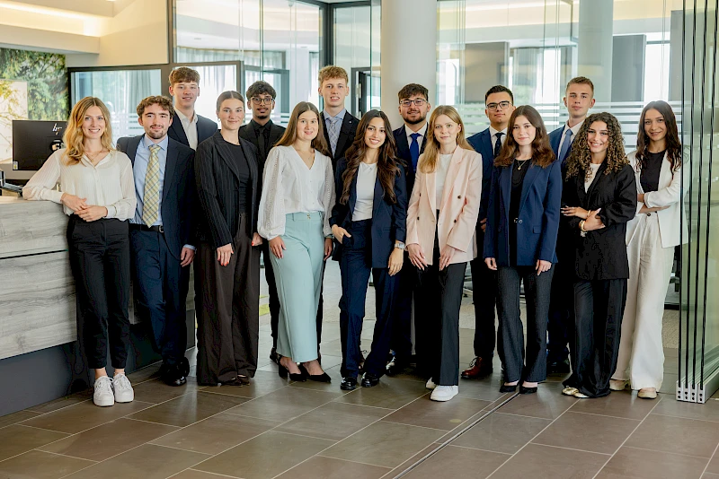 14 neue Auszubildende der Volksbank Oberberg stehen gemeinsam mit Ausbildungsleiterin Sarina Scherbaum in der Hauptstelle in Wiehl. Die Gruppe lächelt in die Kamera und markiert den gemeinsamen Start in die Ausbildung zum 1. August 2026.
