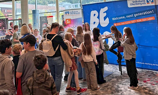 Bela und Charlotte Plass sitzen an einem Tisch im SEVEN Kinocenter Gummersbach und geben Autogramme. Vor ihnen wartet eine Schlange junger Kinogäste.
