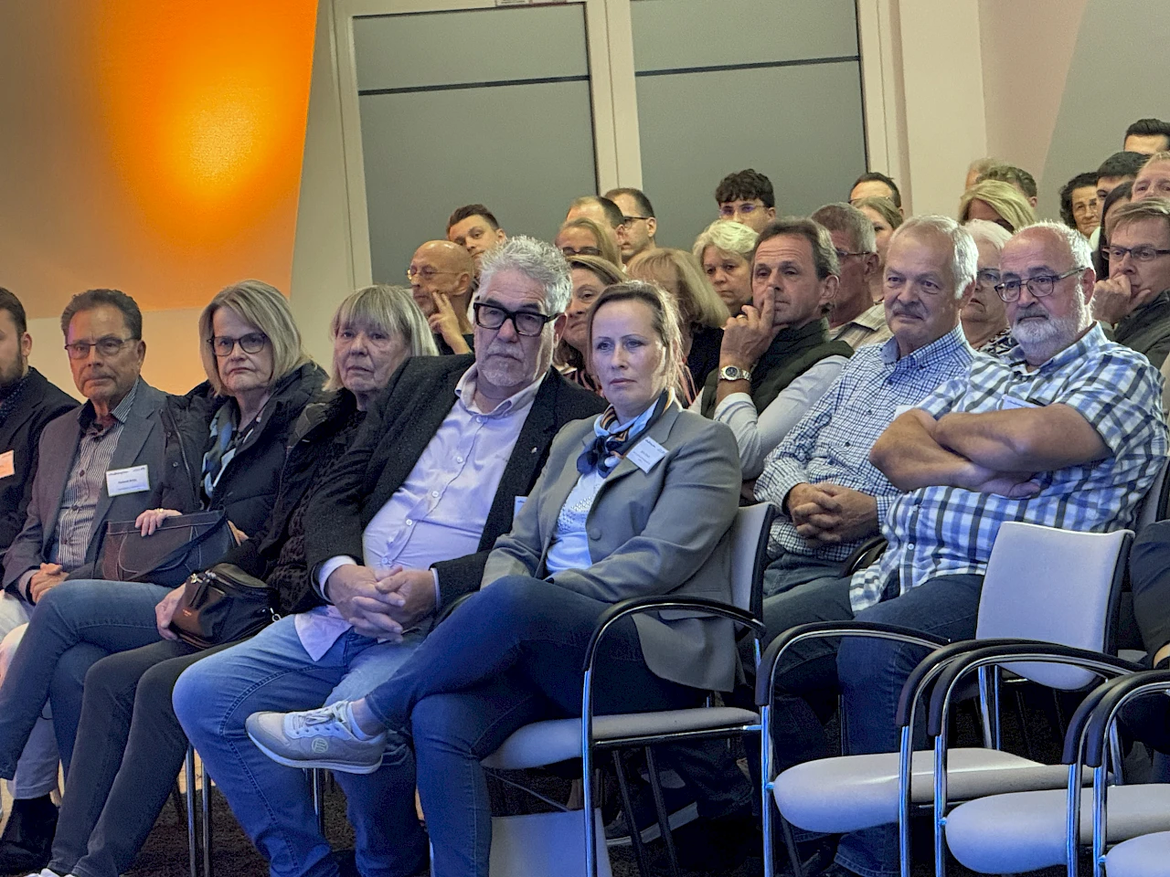Gäste sitzen dicht nebeneinander im Forum der Volksbank Oberberg und verfolgen aufmerksam den Vortrag.