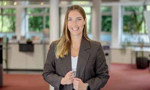 Ann-Kathrin Miebach steht in den R&auml;umen der Volksbank Oberberg und blickt in die Kamera. Die neue Leiterin der Gesch&auml;ftsstelle Bielstein tr&auml;gt einen dunklen Blazer und ein helles Oberteil.
