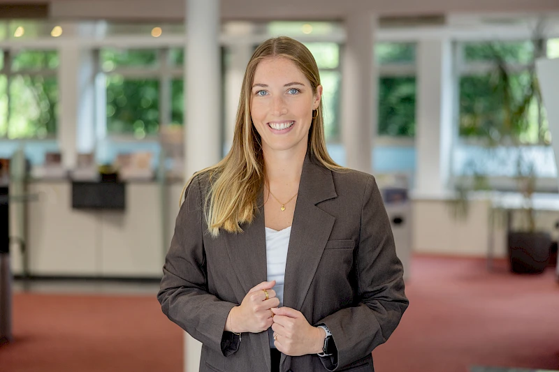 Ann-Kathrin Miebach steht in den Räumen der Volksbank Oberberg und blickt in die Kamera. Die neue Leiterin der Geschäftsstelle Bielstein trägt einen dunklen Blazer und ein helles Oberteil.