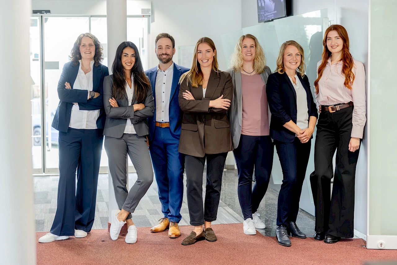 Das Team der Geschäftsstelle Bielstein steht gemeinsam in den Räumen der Volksbank Oberberg. Ann-Kathrin Miebach befindet sich in der Bildmitte, umgeben von ihren Kolleginnen und Kollegen.