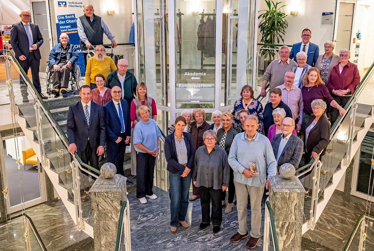 Gruppenfoto beim Ehrungsabend des Sommerwettbewerbs 2026 in der Volksbank Oberberg. Die Teilnehmenden des Wettbewerbs und weitere Beteiligte sind auf einer Treppe versammelt.